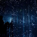 Ein transportabler Dreibein-Grill mit einer großen, runden Grillfläche über Holzkohle, ideal für den Einsatz im Freien und beim Camping.